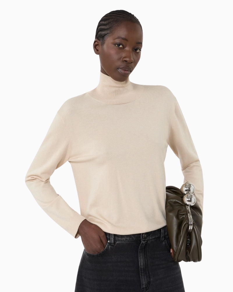 Model wearing beige turtleneck with dark trousers