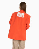 Back view of Alix flowy blazer in orange with bold ALIX THE LABEL print