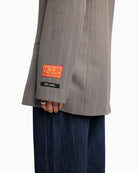 Close-up of Alix logo artwork detail on sleeve of soft grey blazer