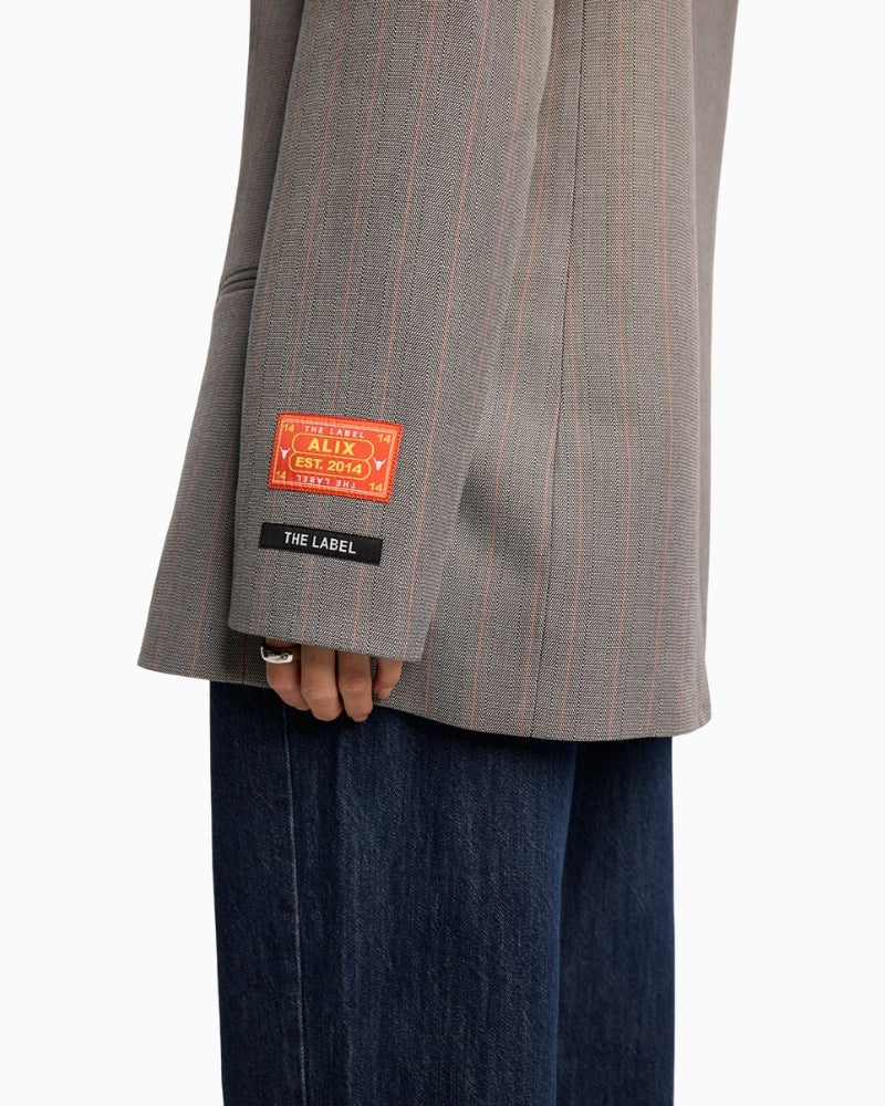 Close-up of Alix logo artwork detail on sleeve of soft grey blazer