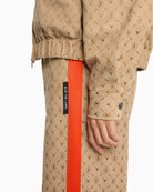 Close-up of jacquard logo fabric and zip front on camel Alix jacket