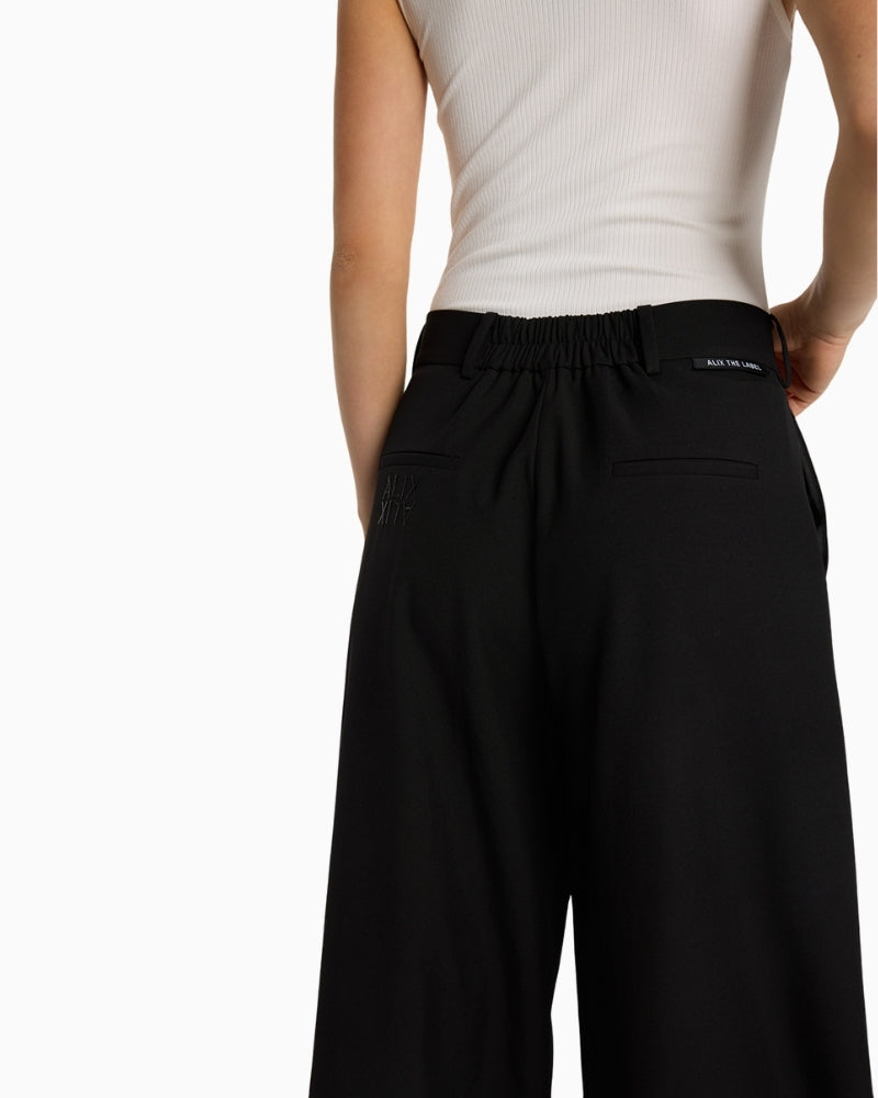 Close-up of subtle Alix logo embroidery and waistband detail on black trousers