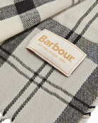 Angled view of monochrome tartan scarf showing brand label