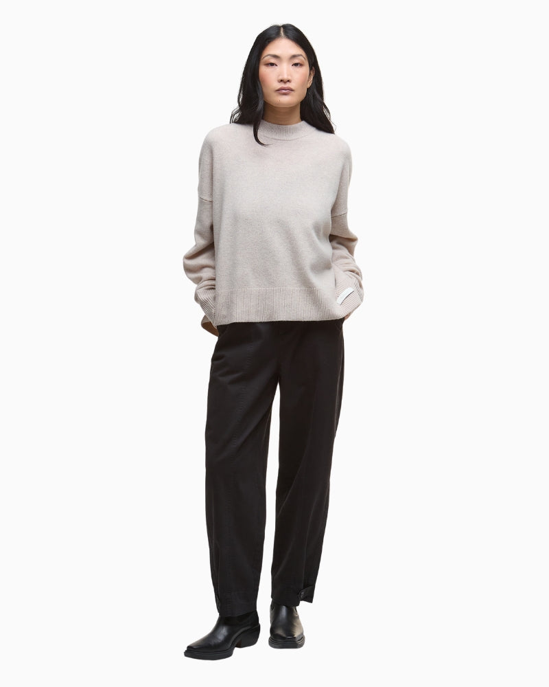 Model wearing beige jumper with relaxed black trousers