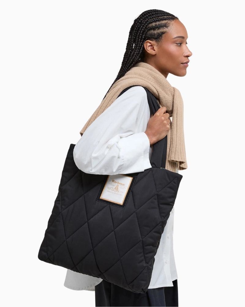 Black quilted Barbour tote carried by top handles, casual everyday styling