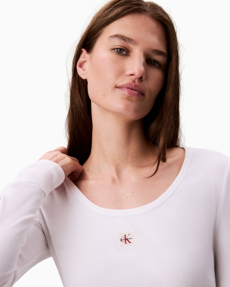 Close-up of CK Jeans woven hem label on white long-sleeve shirt