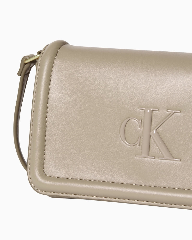 Close-up of embossed Calvin Klein logo on taupe flap