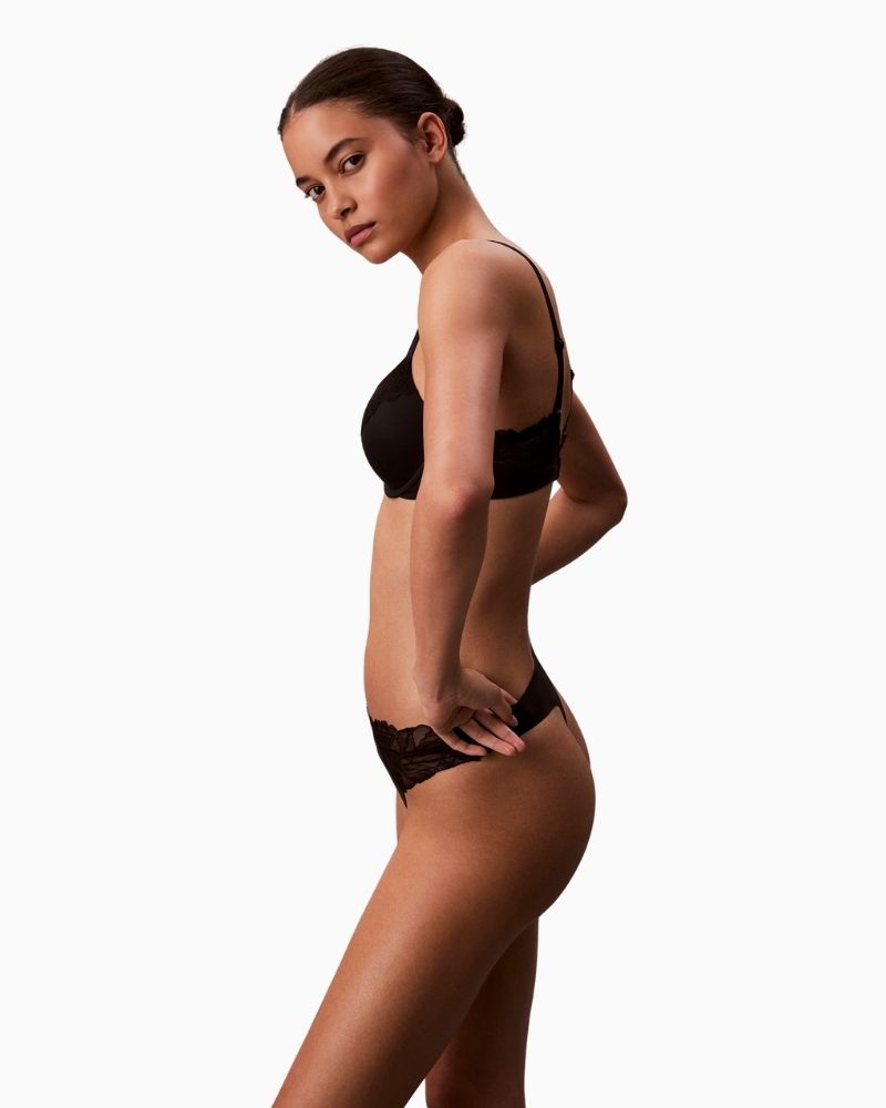 Side view of Calvin Klein lace thong with scalloped trim, cut-out back, and logo detail