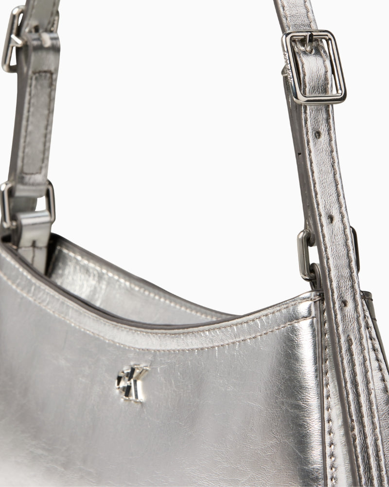 Calvin Klein metallic small shoulder bag in silver, close-up detail of texture and branding – Áines Boutique