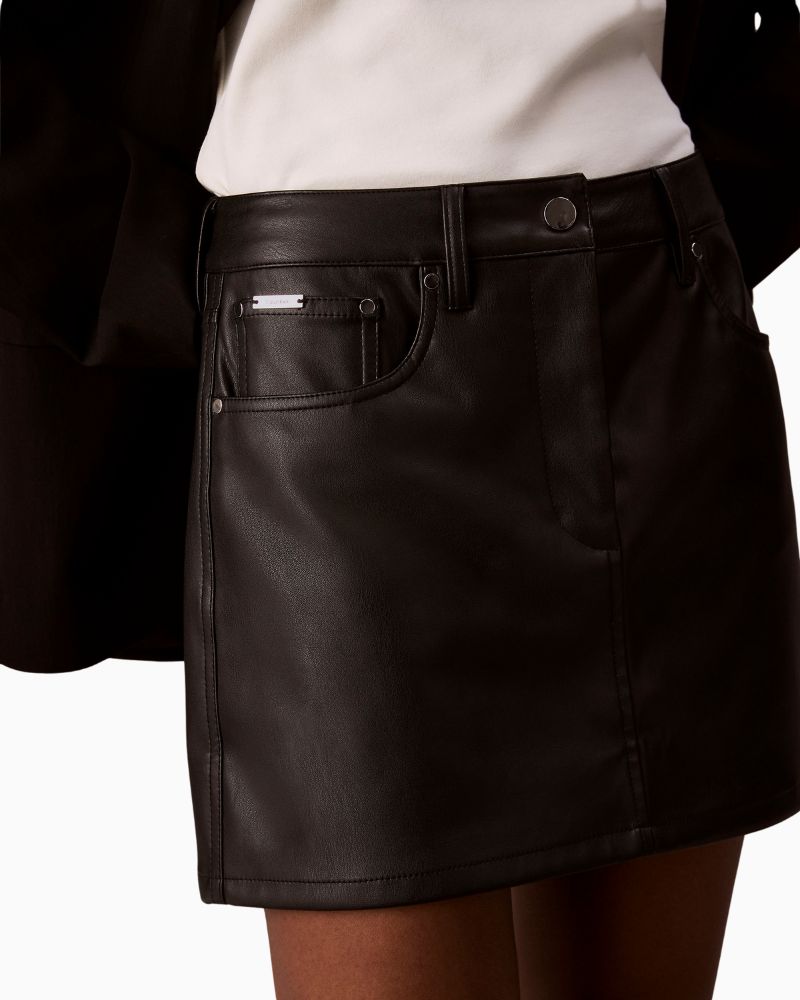 Close up of Calvin Klein faux leather black mini skirt with 5-pocket jeans-style design