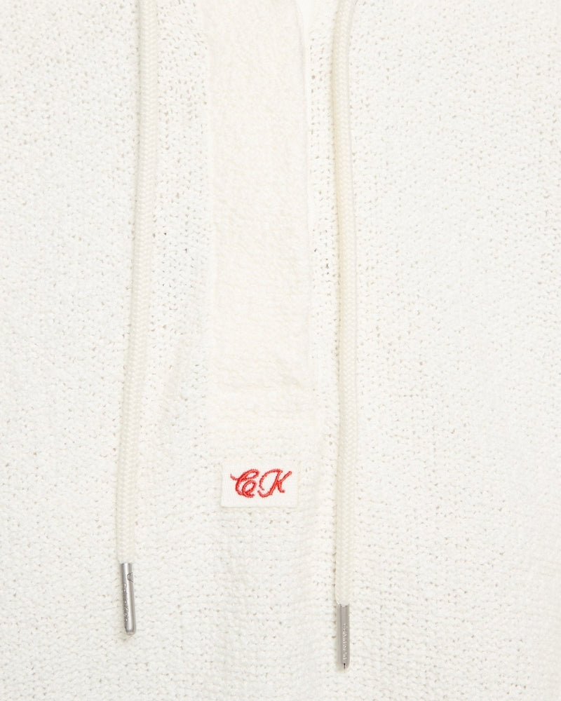 Close-up of Calvin Klein logo embroidery on white hoodie with soft textured finish