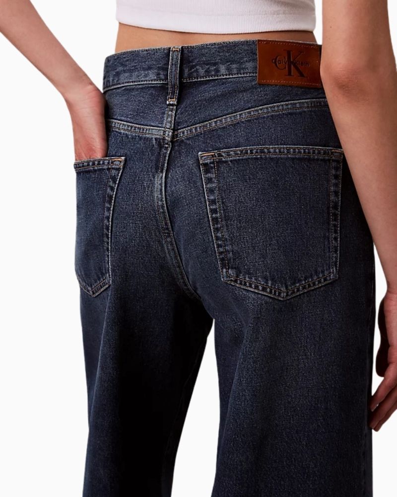 Close up view of Calvin Klein wide leg jeans in dark indigo denim with medium rise and full-length leg