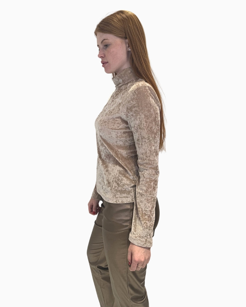 Side profile of a woman wearing a beige crushed velvet top, showing the high poloneck collar.