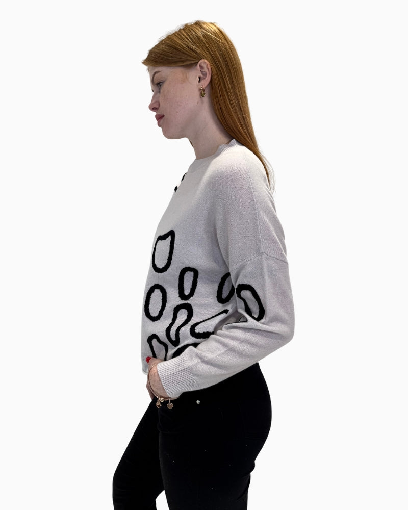 Side profile of model in the Faber Woman cream abstract print jumper and black trousers
