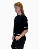 Side profile of the black fine-knit jumper showing the elbow-length sleeves