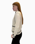 Side view of cream Faber cardigan with long sleeves and black edging