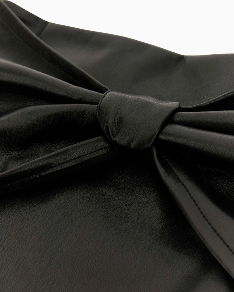 Close‑up of faux leather texture and bow embellishment on Guess mini skirt