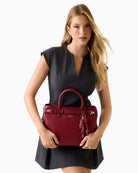 Front view of structured red handbag with twin handles and zip closure