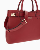 Close-up of detachable charm and Guess logo on red handbag