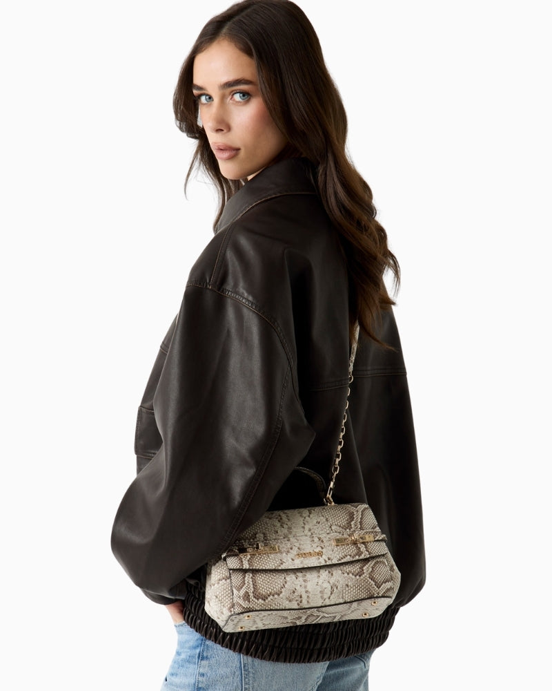 Woman wearing Guess Melinda python print handbag beige side view – Áines Boutique