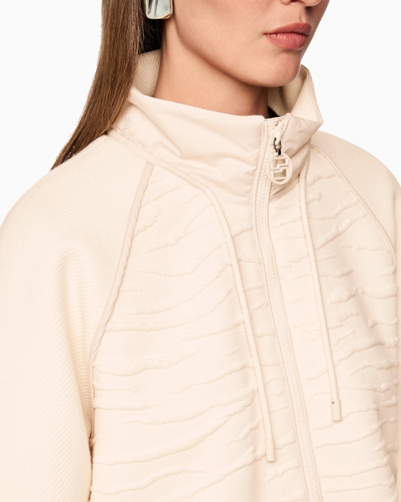 Close-up of mixed textures: ribbed sleeve, printed front panel