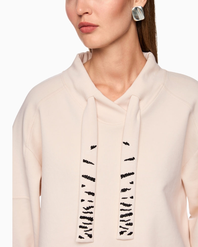 Close-up of bead appliqué on drawstring collar in cream sweatshirt