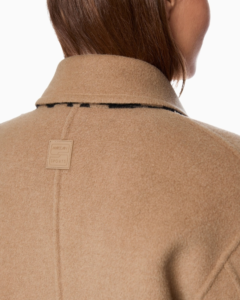Back view of beige side of coat showing clean, straight fit and open pockets