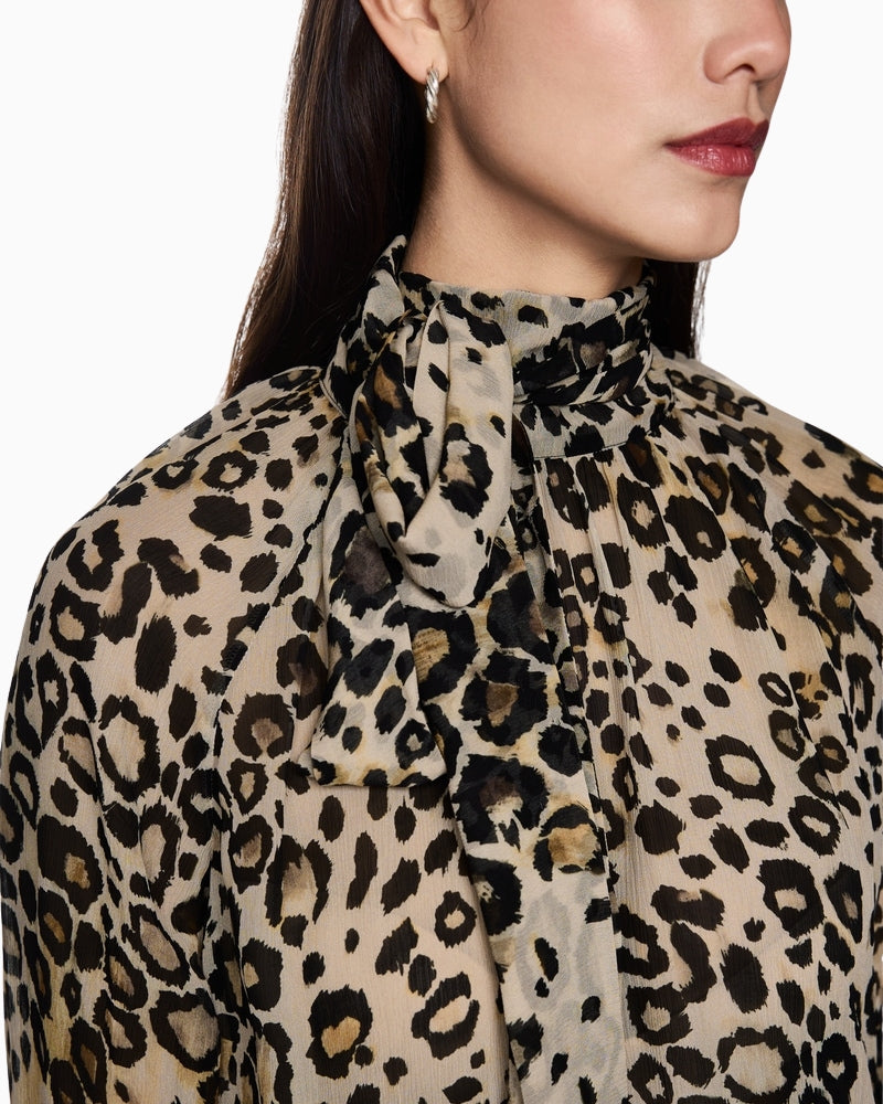 Close-up of balloon sleeves and bow neckline on leopard blouse