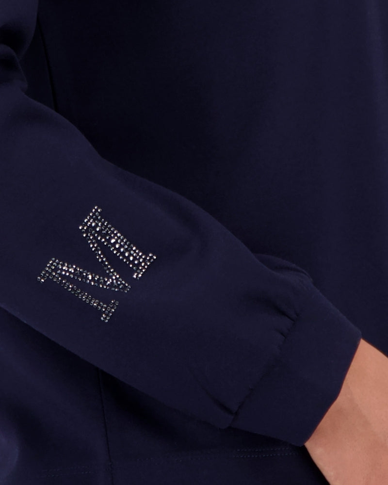 Close-up of rhinestone “M” on sleeve of navy sweatshirt