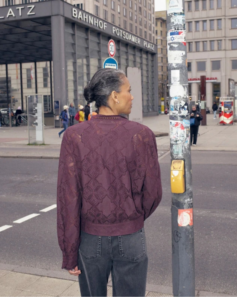 Model wearing black lace shirt by Mos Mosh styled over a camisole for smart-casual look