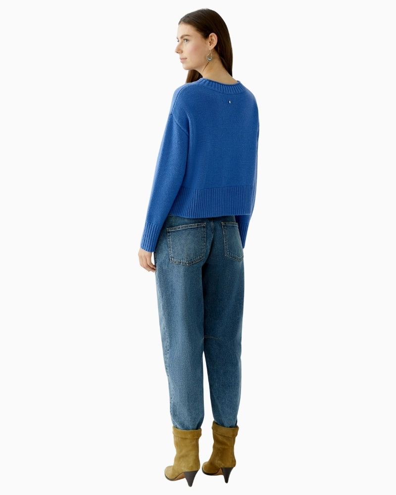 Back view of blue cropped pullover with overcut shoulders