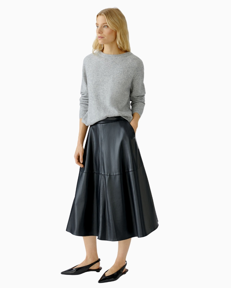 Model wearing skirt styled with knit and boots