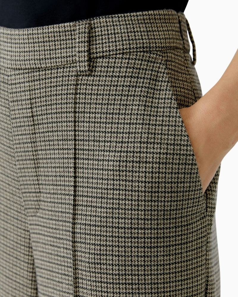 Close-up of houndstooth fabric and front piping detail on smart trousers