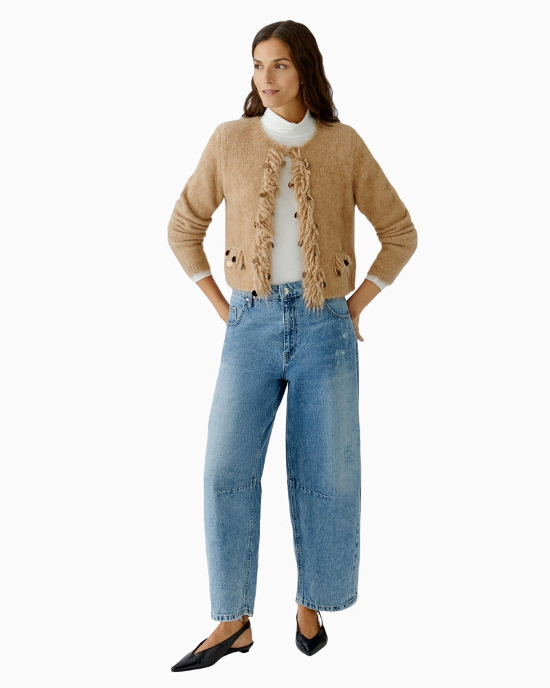 Model wearing beige cropped knit jacket styled with trousers