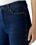 Detail of rivets on pockets and side seams of dark blue jeans
