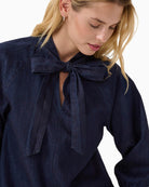 Close-up of neckline bow detail and fabric texture on Sassi shirt