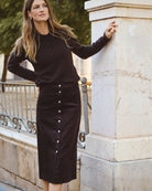 Model wearing brown midi skirt styled with knit jumper and boots
