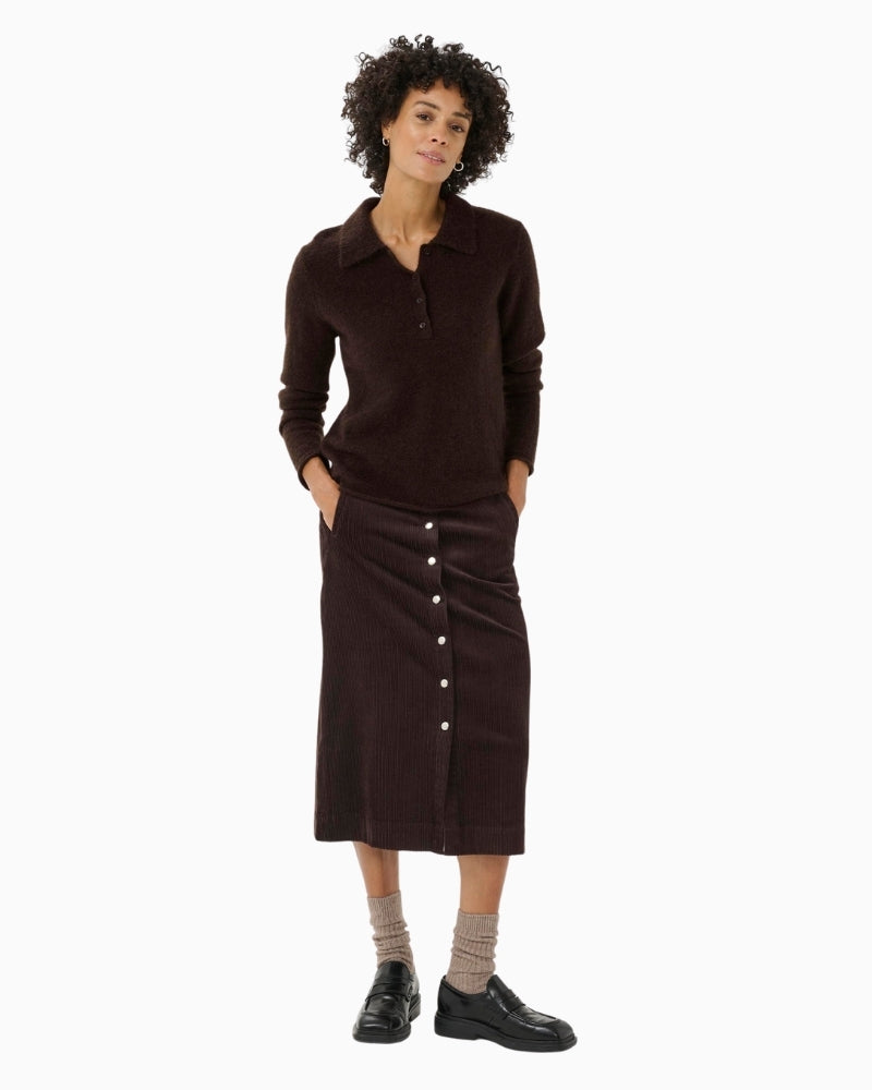 Model wearing brown midi skirt styled with knit jumper and boots
