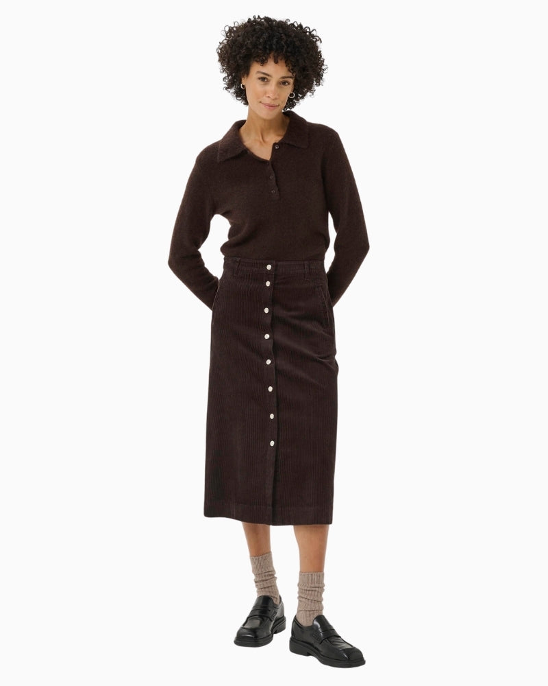 Model wearing brown midi skirt styled with knit jumper and boots