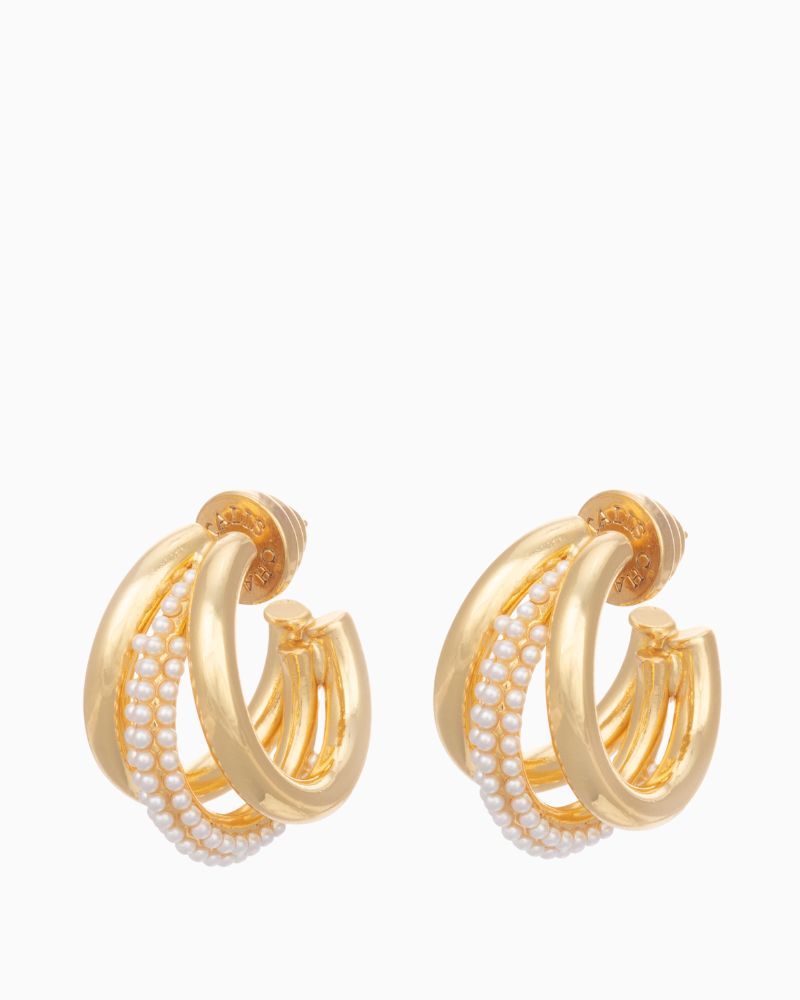 Close-up of triple gold hoop earrings featuring pearl details