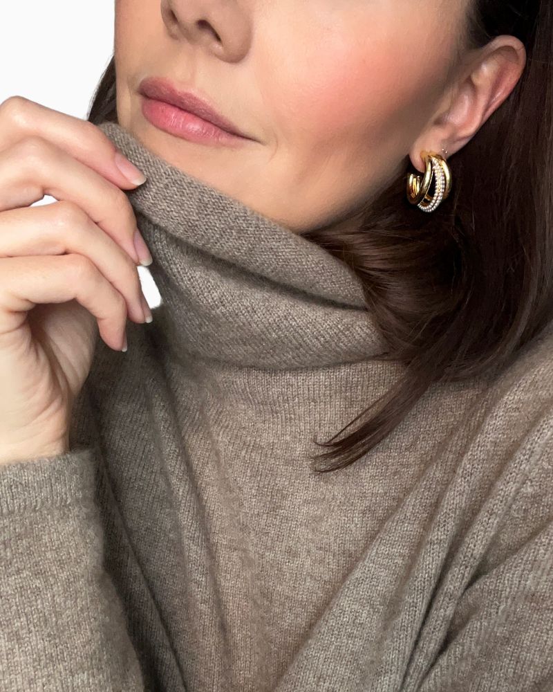 Pair of gold and pearl claw hoop earrings shown with linen drawstring pouch