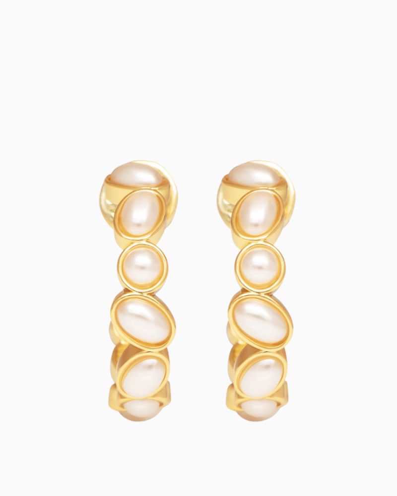 Close-up of modern gold and pearl hoop earrings in rounded design