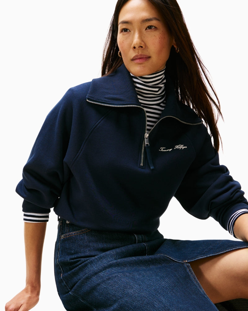 Close-up of embroidered Tommy Hilfiger script on navy sweater