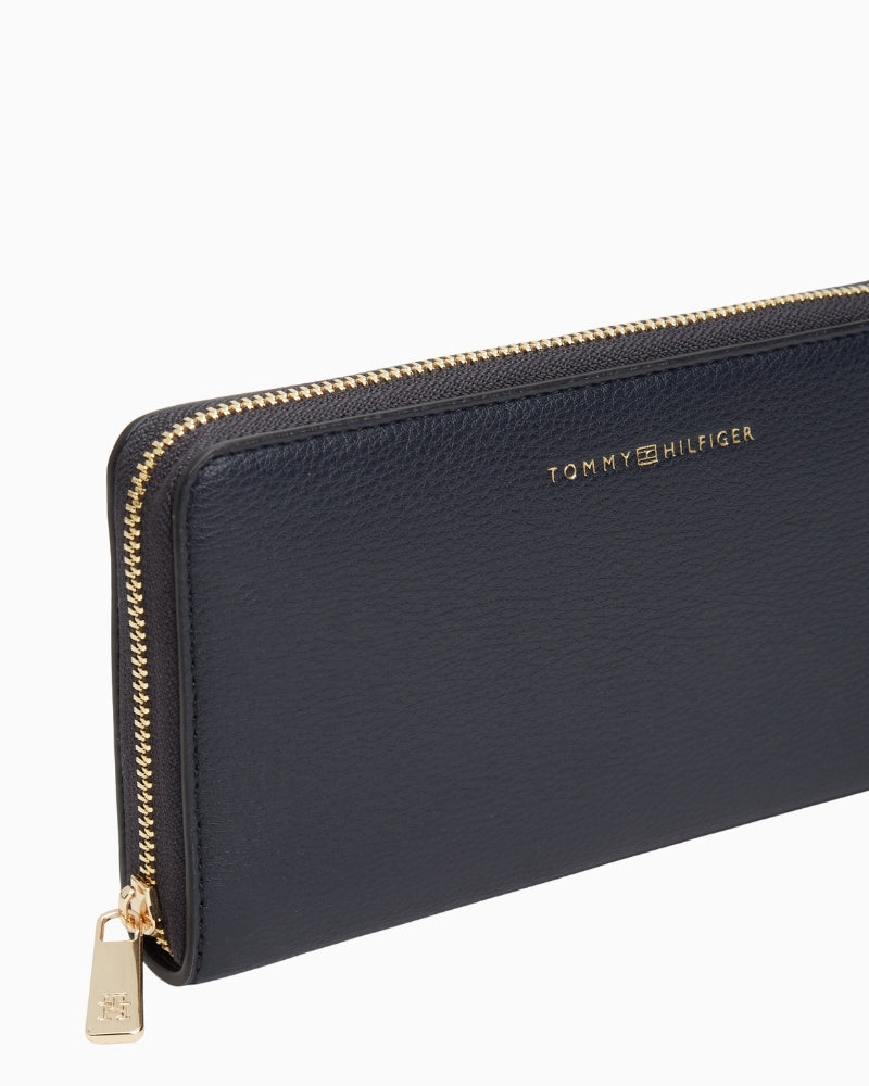 Side view of navy Tommy wallet with zip closure and slim profile