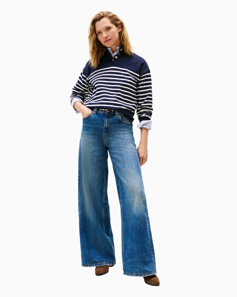 Model styled in the striped mock neck sweater with jeans, standing in a casual autumn setting.