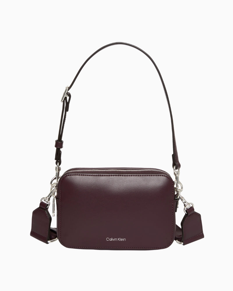 Front view of the Calvin Klein Webbing Double Strap Camera Bag in brown with gold-tone zip and logo detail.