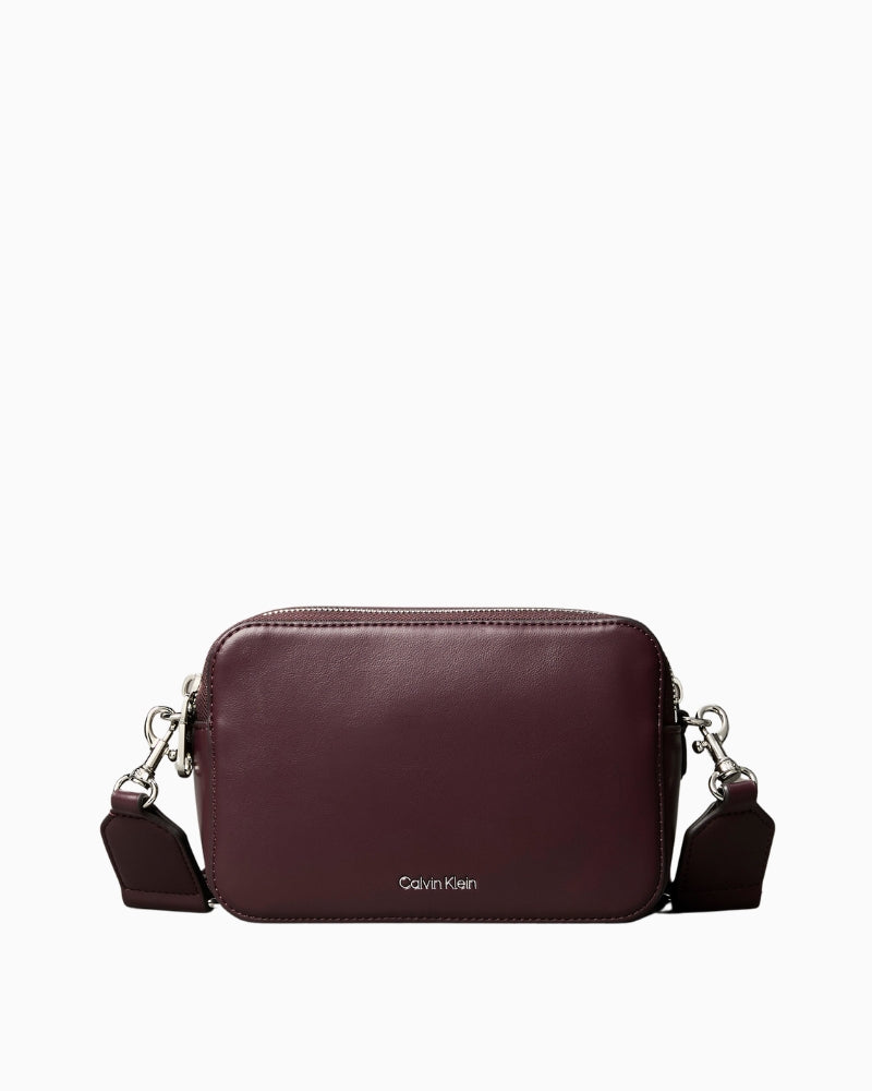 Close-up of the double webbing straps and zip fastening on the Calvin Klein brown crossbody camera bag.