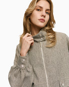 Close-up of high neck with button closure and zip fastening on grey herringbone jacket