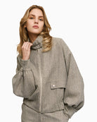 Front view of grey herringbone jacket with high neck, puff sleeves and flap pockets