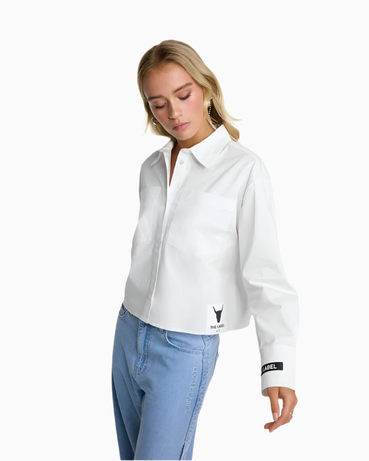 Model wearing Alix The Label cropped white blouse with front logo patch